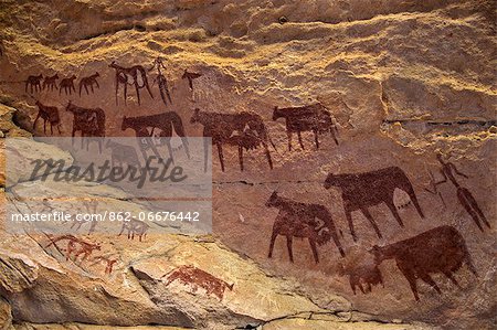 Chad, Taore Koaole, Ennedi, Sahara. Bichrome paintings of cattle and two human figures decorate the sandstone wall of a cave.