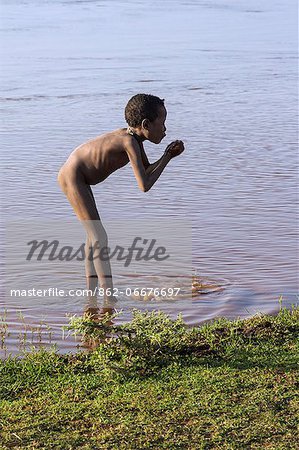 A young Dassanech boy drinks muddy water from the Omo River, Ethiopia