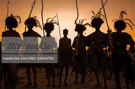 Dassanech men dressed in ceremonial regalia at sunset after participating in a Dimi dance, Ethiopia