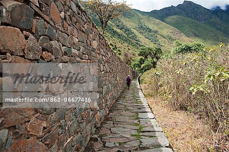 South America, Peru, Cusco, Nusta Hispana. Terraces, a hiker walks next to a long Inca wall and causeway at Choquequirao, built by Tupac Inca Yupanqui and Huayna Capac and situated above the Apurimac valley in the mountains of the Salkantay range