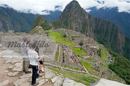 South America, Peru, Cusco, Machu Picchu. Inca trail hikers in front of the World Heritage listed Inka Historic Sanctuary of Machu Picchu with Huayna Picchu mountain behind South America, Peru, Cusco, Machu Picchu. Inca trail hikers in front of the World Heritage listed Inka Historic Sanctuary of Machu Picchu with Huayna Picchu mountain behind