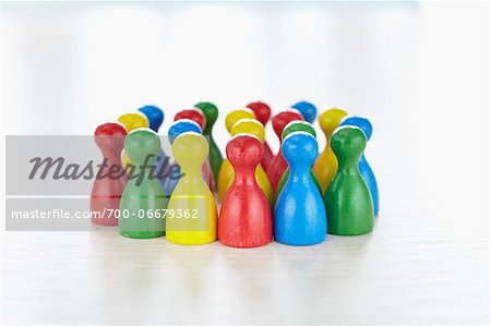 Huddle of multi-colored playing pieces standing together in a group like people