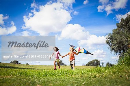 Brother and sister holding hands and playing with a kite Brother and sister holding hands and playing with a kite