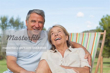 Couple laughing together with woman sitting in deck chair