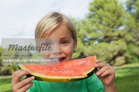 Cute blonde boy eating watermelon