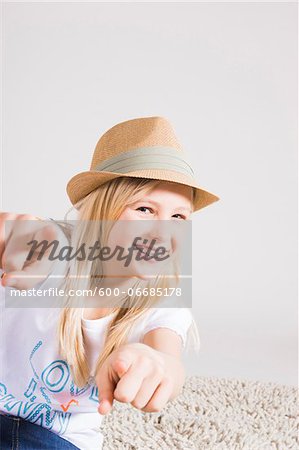 Portrait of Girl wearing Hat and Pointing at Camera in Studio