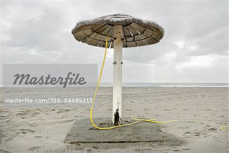 UMBRELLA ON THE BEACH IN WINTER ON A CLOUDY DAY, OSTIA LIDO, ROME, ITALY