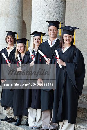 Happy smiling graduates posing in single line with columns in background