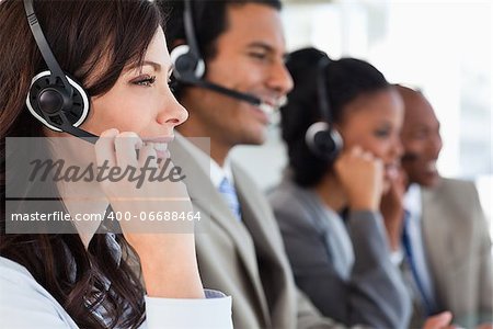 Young employee working with a headset and accompanied by her team