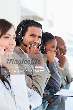 Young smiling call centre worker working among his working team
