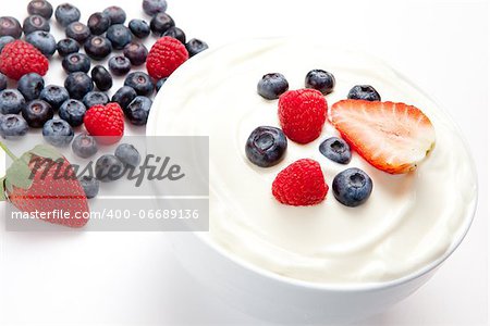 Bowl of cream with berries against a white background