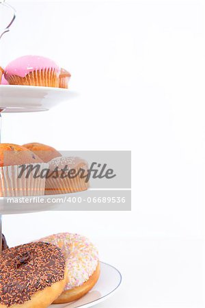 Close up of many cakes placed on three white plates against a white background