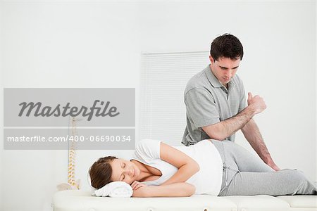 Woman lying on the side while being massaging by her doctor in a medical room