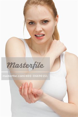 Blonde woman touching her painful elbow against white background