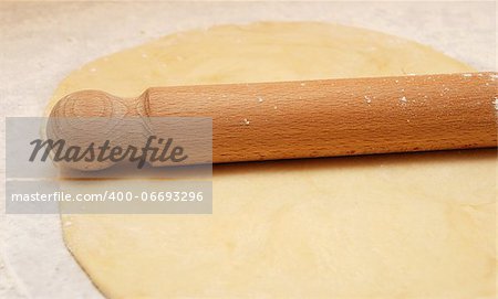 Fresh pastry rolled out on a floured surface with a wooden rolling pin
