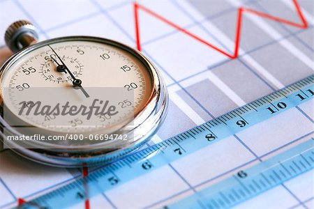 Business concept. Closeup of stopwatch and ruler on paper background with business chart