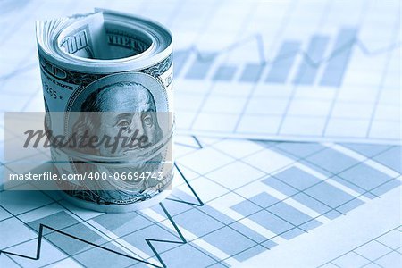 Business concept. Roll of dollars on paper background with business chart