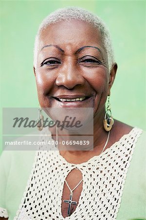 Old black woman portrait, lady in elegant clothes smiling on green background