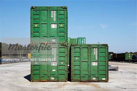 Green containers on a railway platform with freight trains