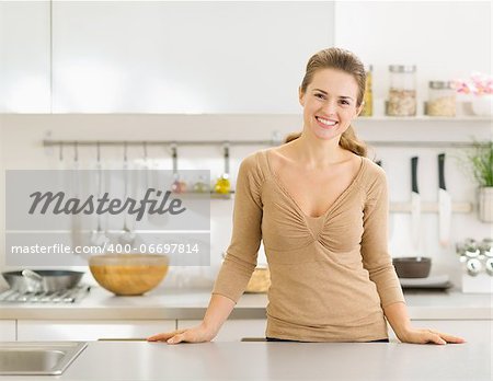 Portrait of smiling young housewife in modern kitchen