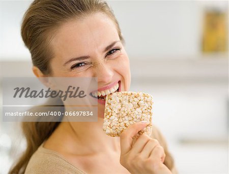 Happy young woman eating crisp bread