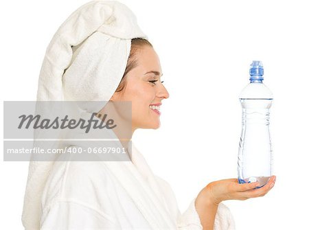 Happy young woman in bathrobe holding bottle with water
