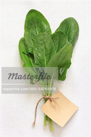 Fresh green spinach leaves on a white cloth with a label.