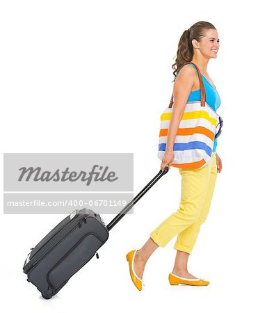 Young tourist woman with wheel bag going sideways