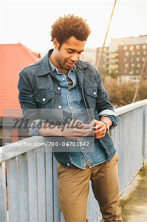 Young man texting on an iPhone in an urban setting. Young man texting on an iPhone in an urban setting.