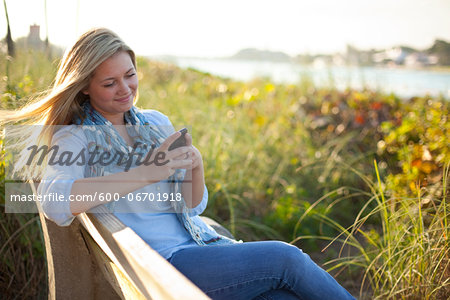 Young Woman Sitting on Bench at Beach, Texting on Cell Phone, Jupiter, Palm Beach County, Florida, USA