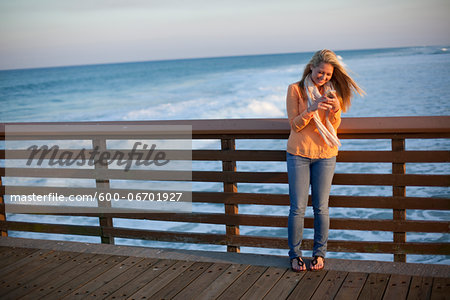 Young Woman Standing on Pier at Beach, Texting on Cell Phone, Jupiter, Palm Beach County, Florida, USA