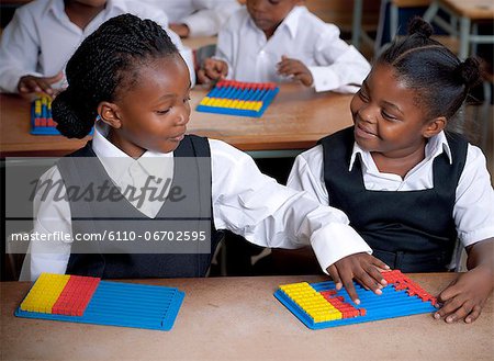 Young African schoolgirls working on abacuses inside a classroom