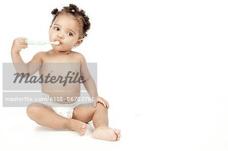 An infant sits in front of a white background.