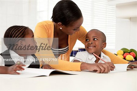 Young African mother helping her children with their homework