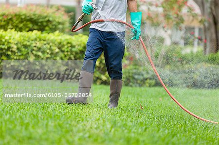 Pest control technician using high pressure spray gun and hose with heavy duty gloves