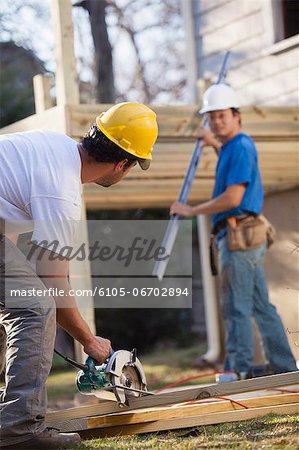 Carpenters using circular saw at home deck construction