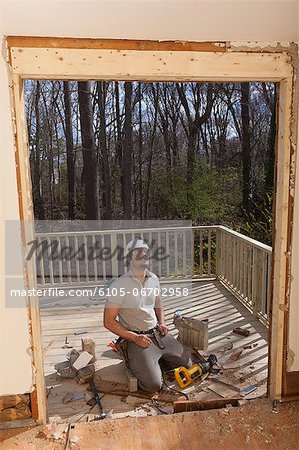 Hispanic carpenter preparing doorway for new frame to side of house