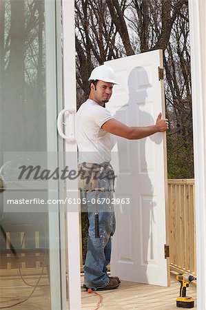 Hispanic carpenter about to make new door installation on house