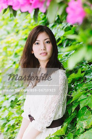 Japanese woman surrounded by green leaves looking at camera