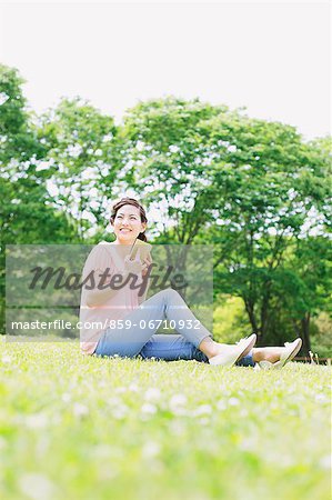 Japanese woman with a book relaxing in a meadow