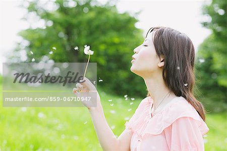 Japanese woman blowing on a Dandelion