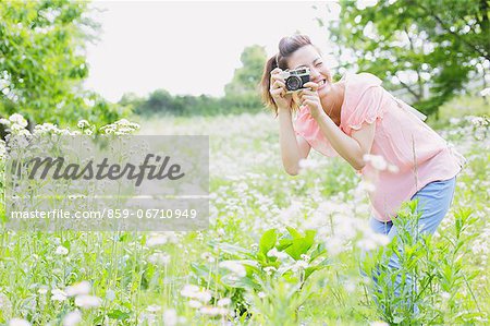 Japanese woman taking pictures in a meadow