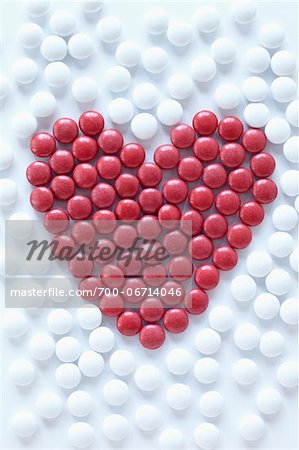 close-up of red pills arranged into heart shape amongst white pills