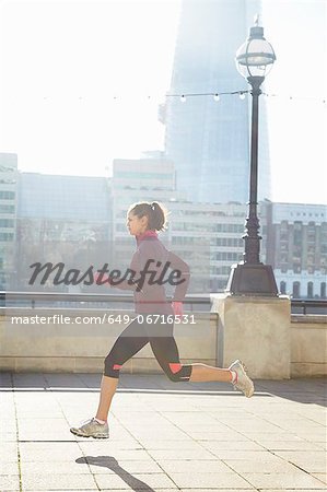 Woman running on urban bridge