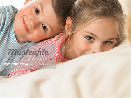 Children smiling together on bed