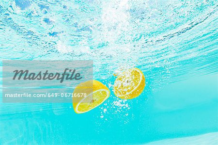 Sliced lemon splashing into water