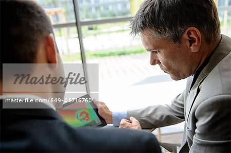 Businessmen using tablet computer at desk