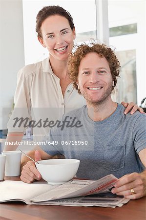 Couple reading newspaper at breakfast