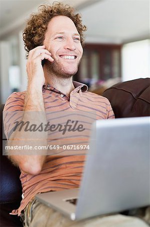 Man on laptop talking on cell phone