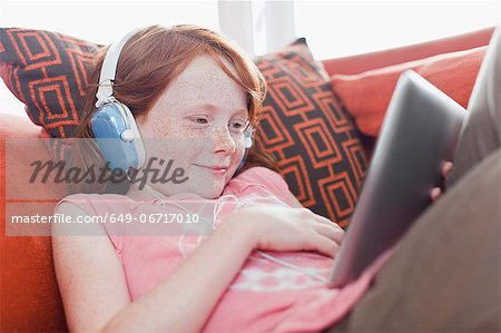 Girl in headphones using tablet computer